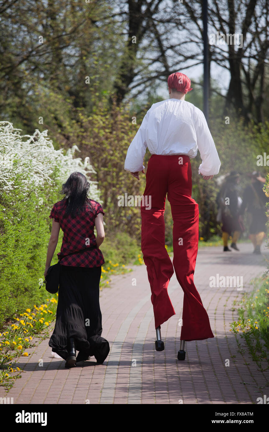 Uomo con i capelli rossi e pantaloni camminando su palafitte in posizione di parcheggio con il gotico vestito ragazza al suo fianco in abiti d'epoca, originale unico giovane Foto Stock