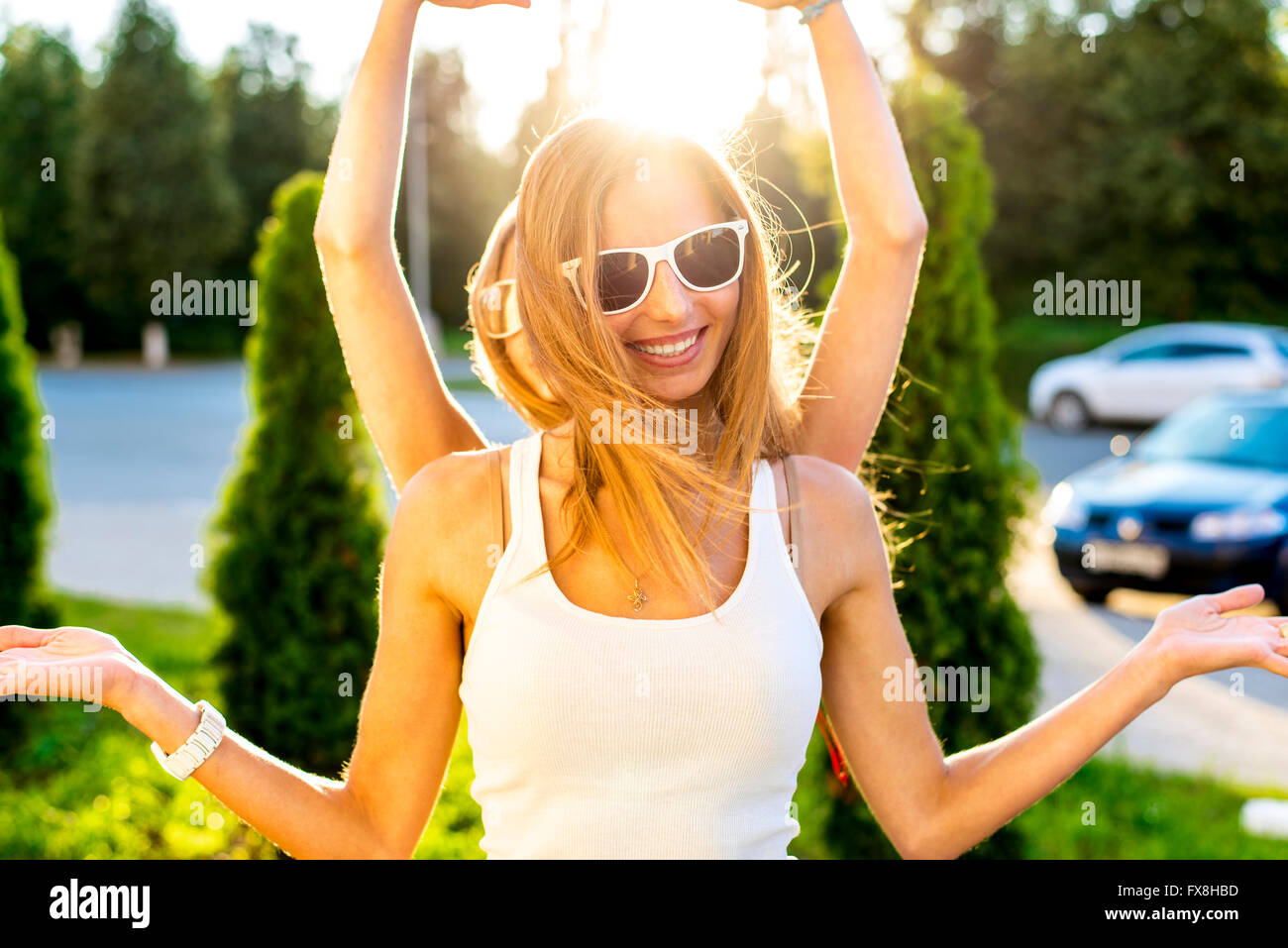 Felice ragazza sorridente soleggiate giornate estive sulla strada ingannare le armi a lato e in cima Foto Stock