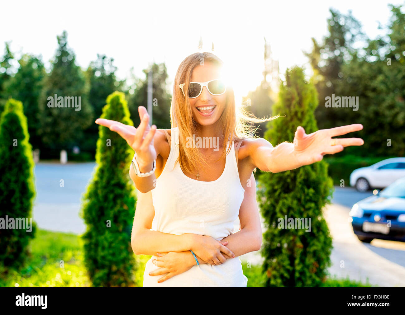 Felice ragazza sorridente soleggiate giornate estive sulla strada ingannare le armi a lato e in cima Foto Stock