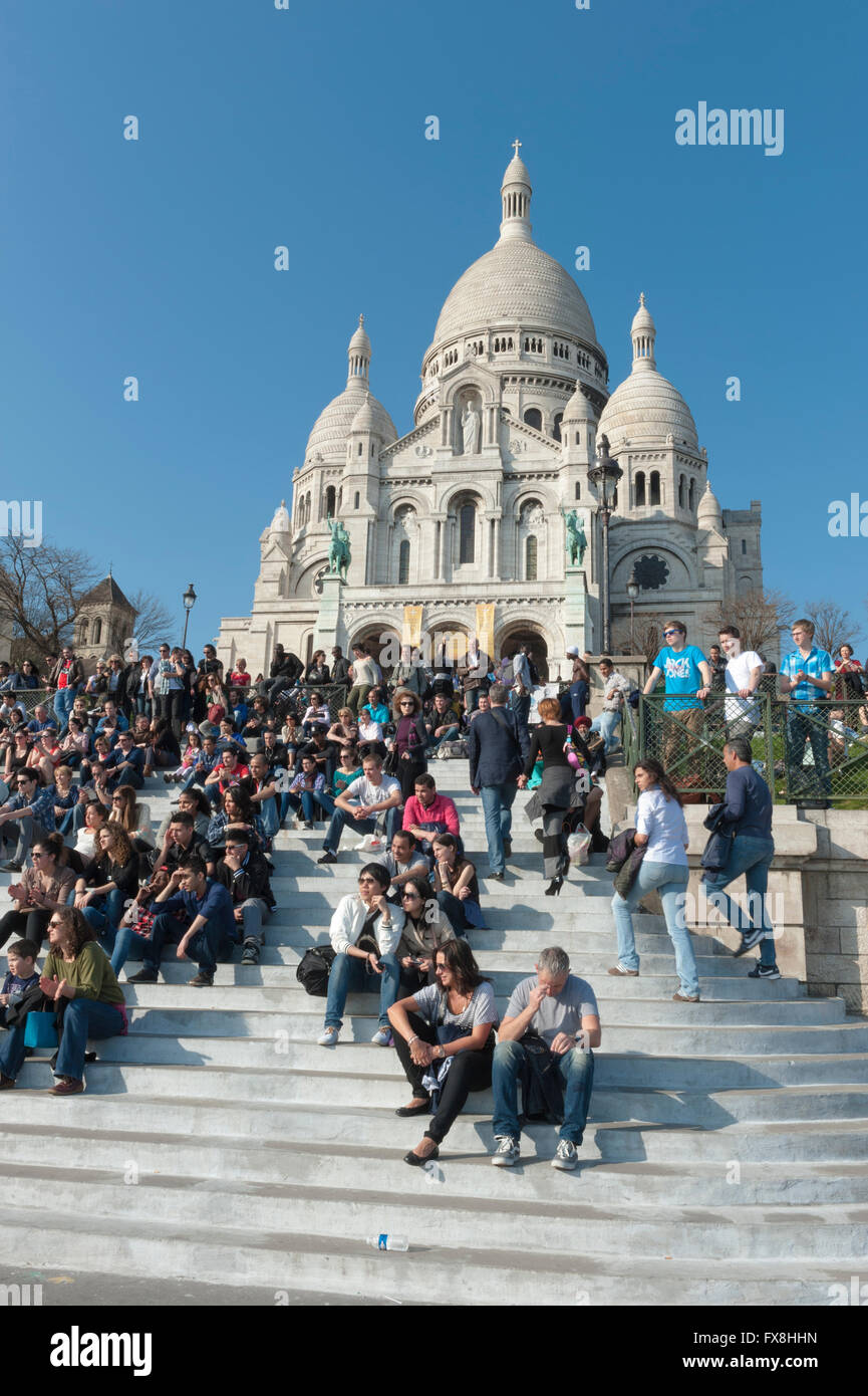La folla seduti sui gradini al Sacre Coeur Paris Foto Stock