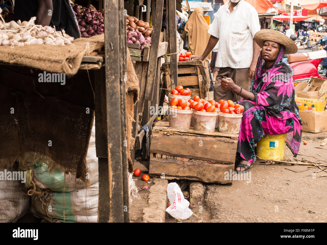 Donna africana indossando abiti tradizionali pomodori di vendita in un mercato locale. Foto Stock