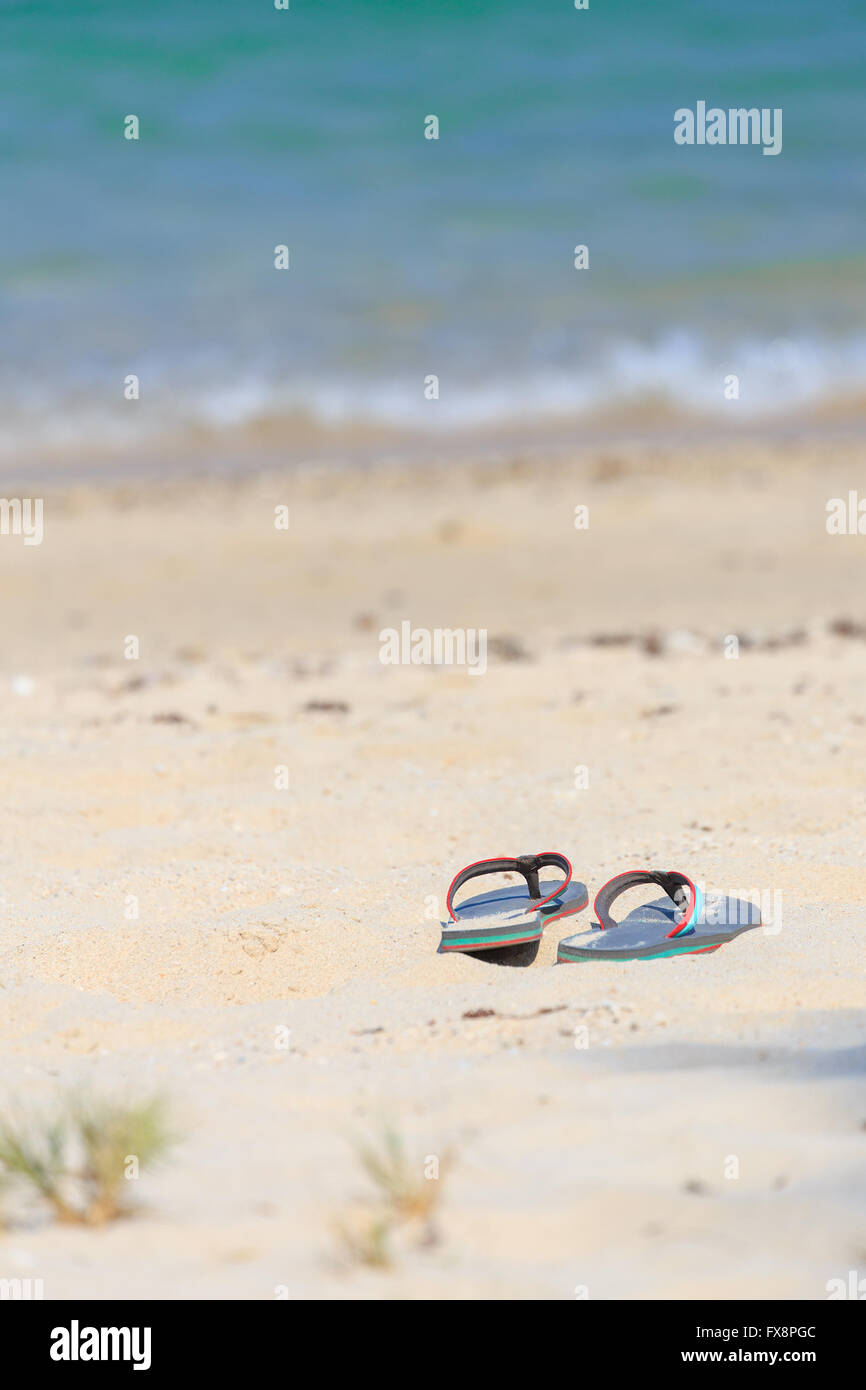 Messa a fuoco ravvicinata sulla pianura grigio sandalo di donna sulla spiaggia di sabbia bianca Foto Stock