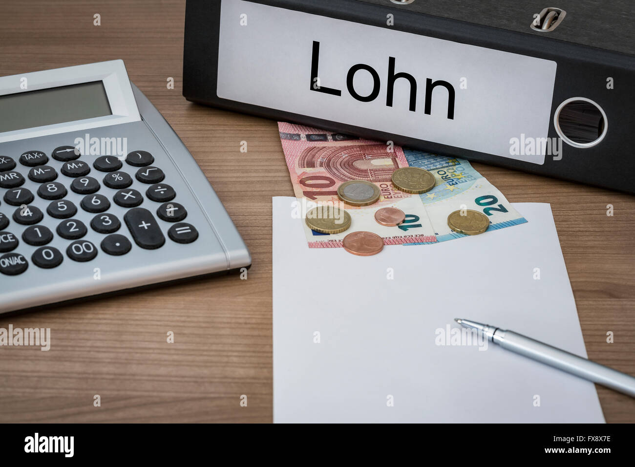 Lohn (tedesco salari) scritto su un legante su un banco con denaro euro calcolatrice foglio bianco e penna Foto Stock