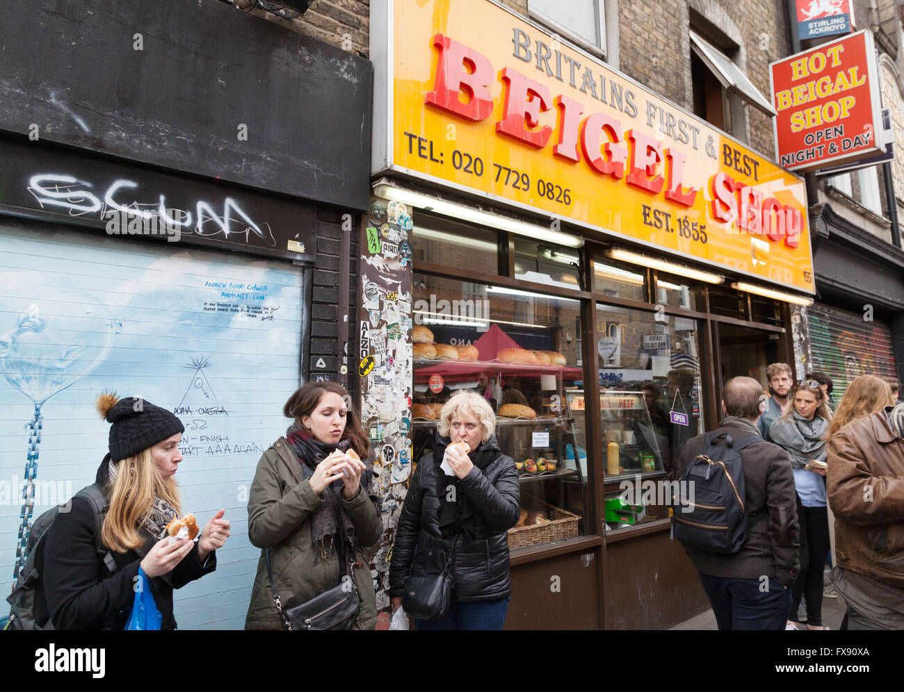 Persone mangiare beigels al di fuori del negozio di Beigel, Brick Lane, Spitalfields, London East End, Regno Unito Foto Stock