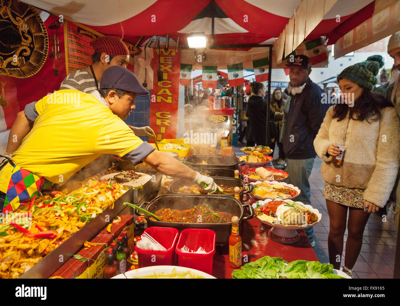 Street food Londra; persone ad acquistare cibo messicano in un cibo di strada, di stallo Brick Lane domenica sistemazione, Spitalfields, London East End, Regno Unito Foto Stock