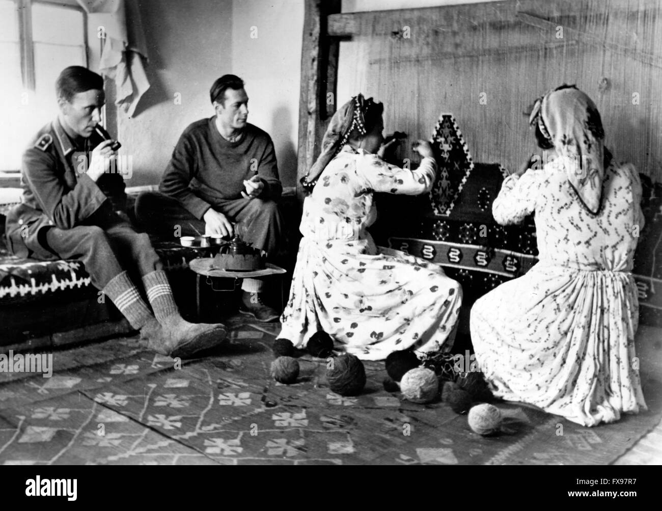 La foto della propaganda nazista mostra i soldati della Wehrmacht tedesca che guardano le donne bosniache che lavorano a maglia il tappeto. La foto è stata scattata nel gennaio 1944. Fotoarchiv für Zeitgeschichtee - SENZA FILI - Foto Stock