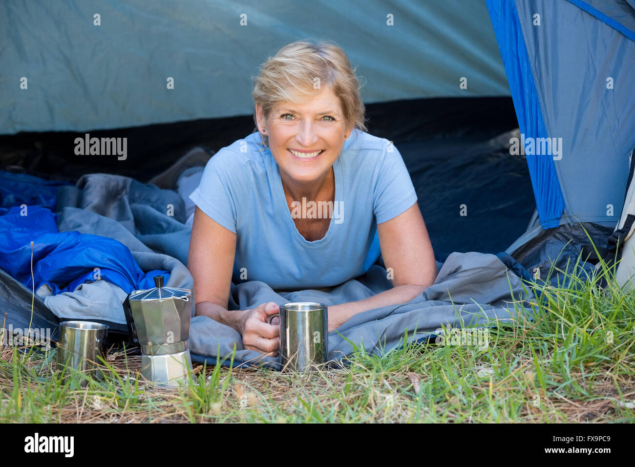 Donna matura posa sorridente e tenendo una tazza Foto Stock