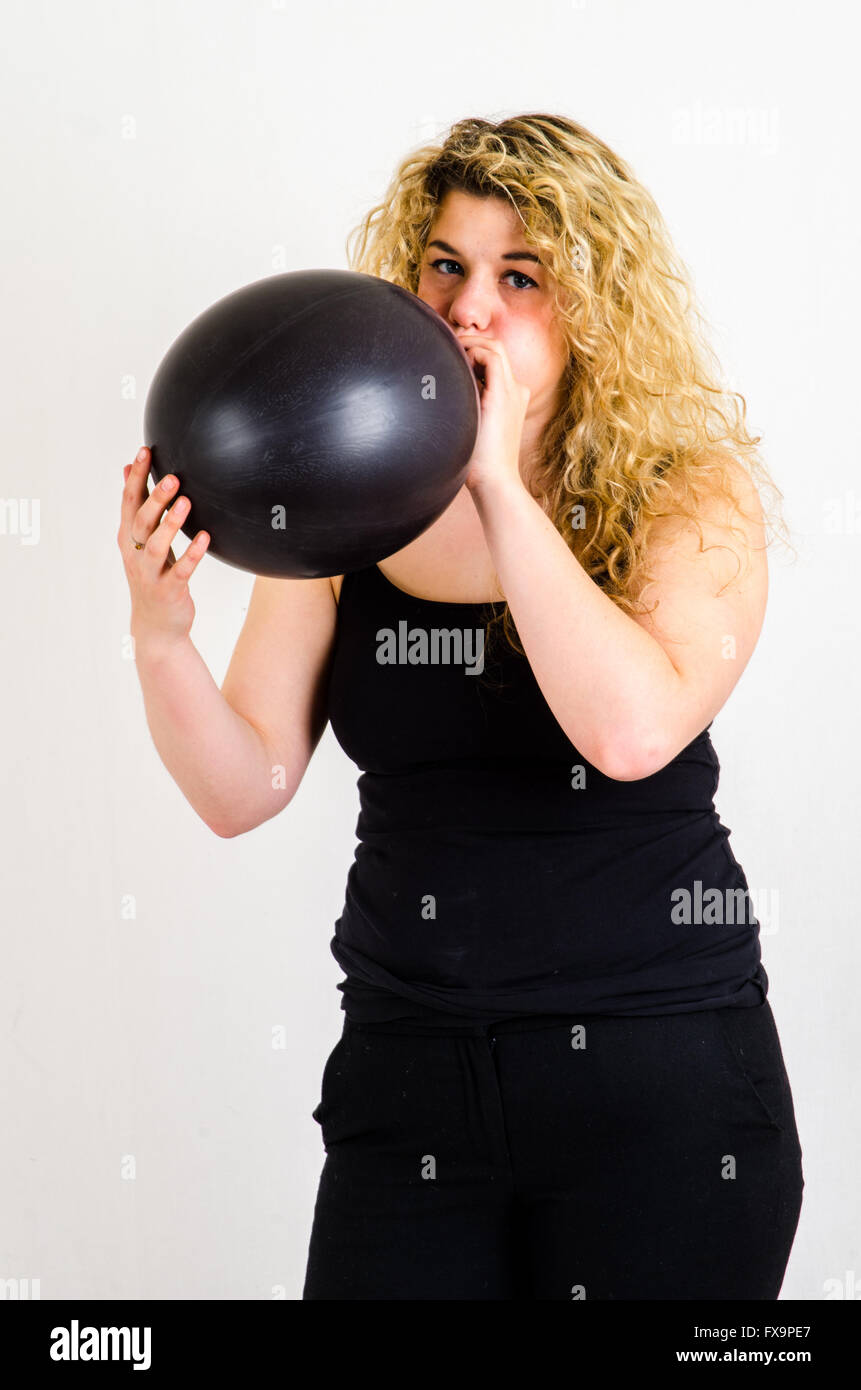 Giovane donna gonfiare un enorme pallone viola per bocca Foto Stock