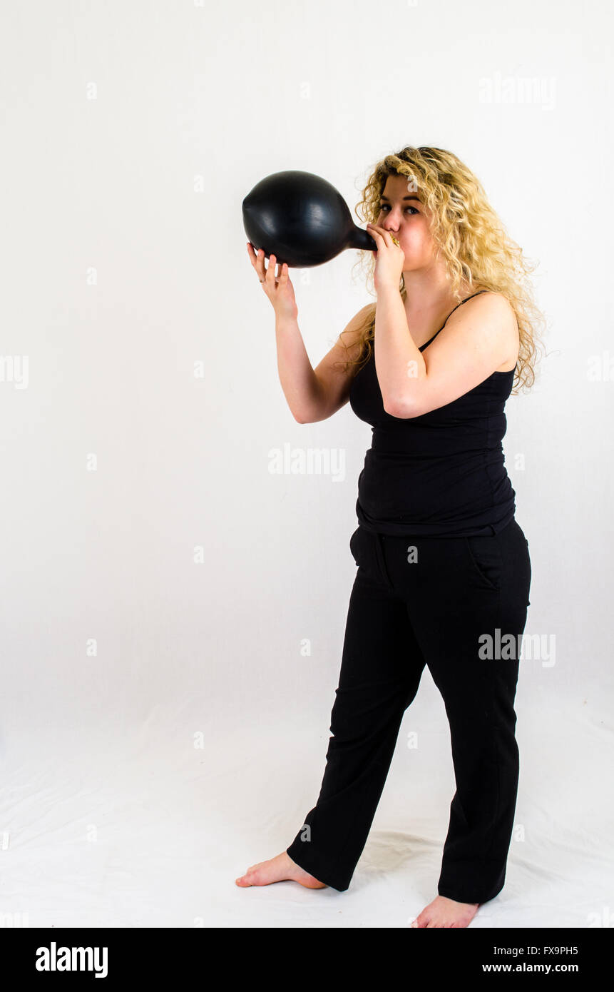 Giovane donna gonfiare un enorme pallone nero per bocca Foto Stock