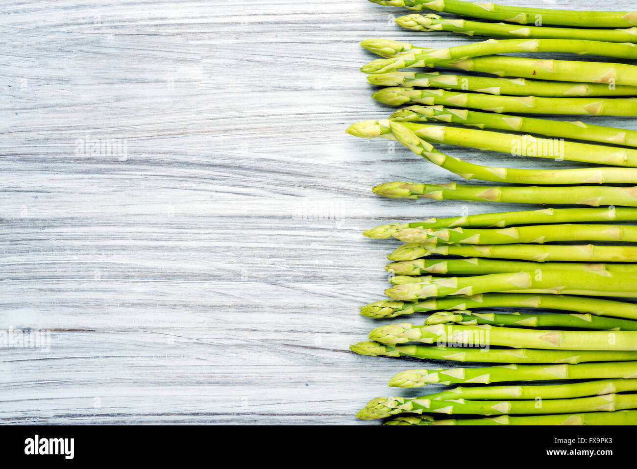 Verde sparagus fresca sulla luce dipinta sullo sfondo di legno. Vista superiore, spazio di copia Foto Stock