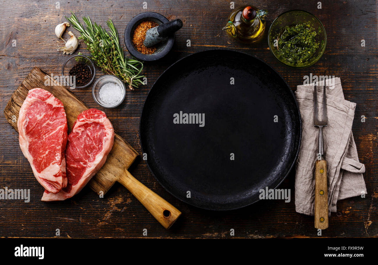 Forma di cuore crudo fresco bistecca di carne controfiletto per due con ingredienti intorno a padella Foto Stock