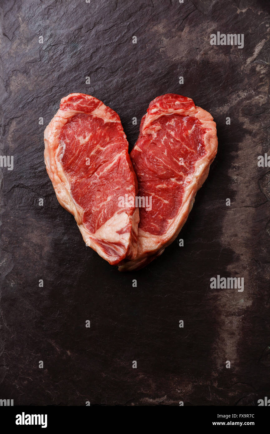 Forma di cuore crudo fresco bistecca di carne controfiletto su pietra ardesia sfondo Foto Stock