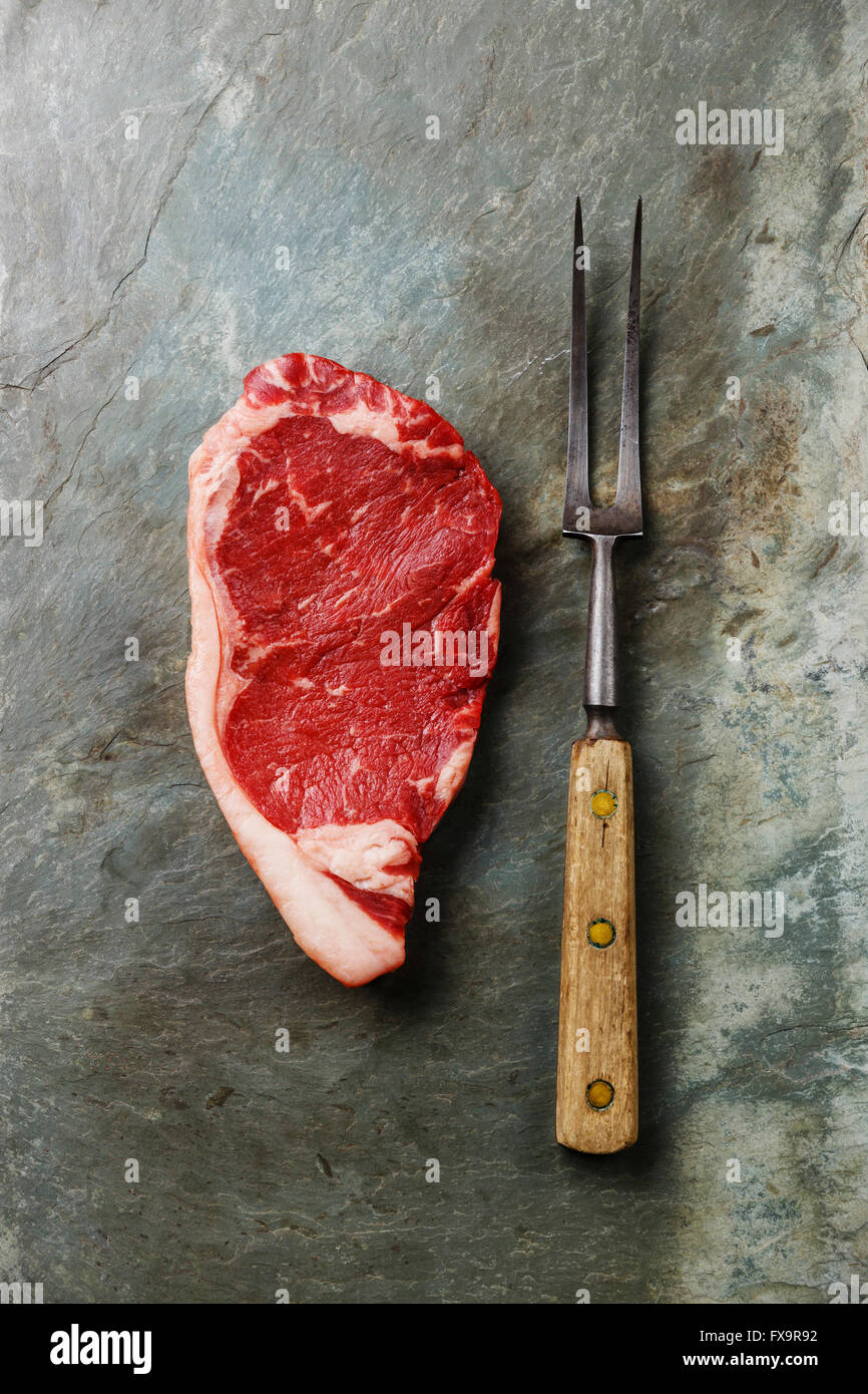 Materie carni fresche bistecca di controfiletto di carne e la forcella sulla pietra grigia sullo sfondo di ardesia Foto Stock