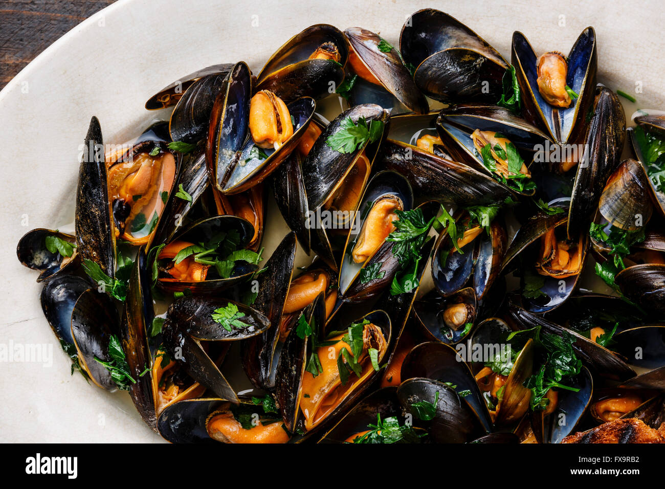Le cozze con il prezzemolo sulla piastra close up Foto Stock