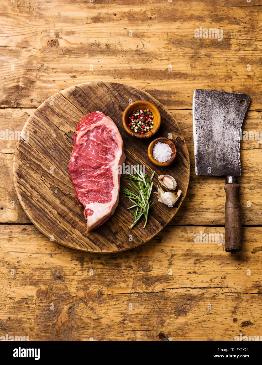 Materie carni fresche bistecca di controfiletto con sale e pepe e carne di macellaio cleaver sul bordo di taglio su sfondo di legno Foto Stock