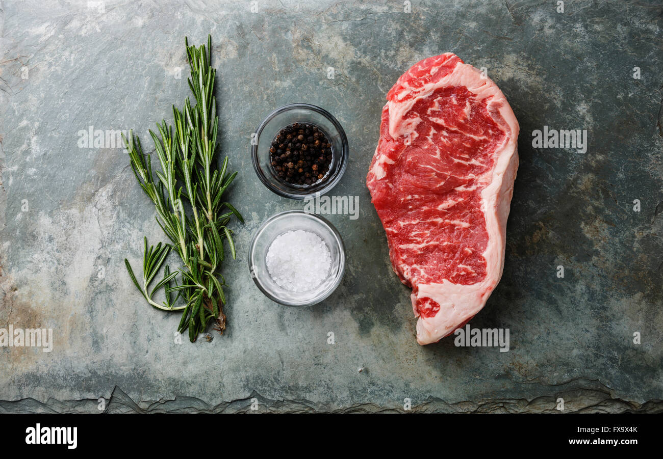 Materie carni fresche bistecca di controfiletto al rosmarino, sale e pepe in pietra sullo sfondo di ardesia Foto Stock