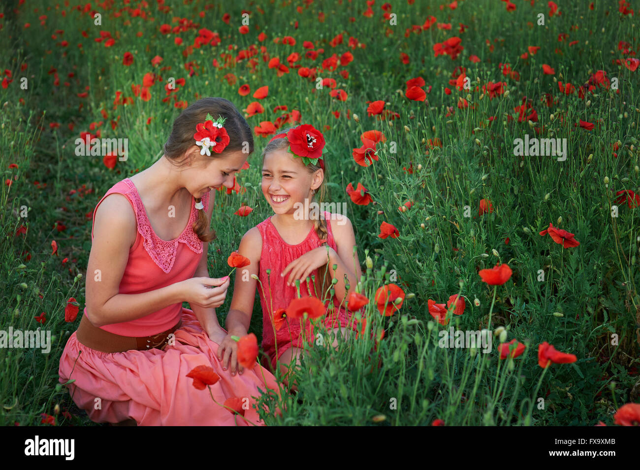 Due ragazze in abito rosso camminando sul campo di papavero Foto Stock