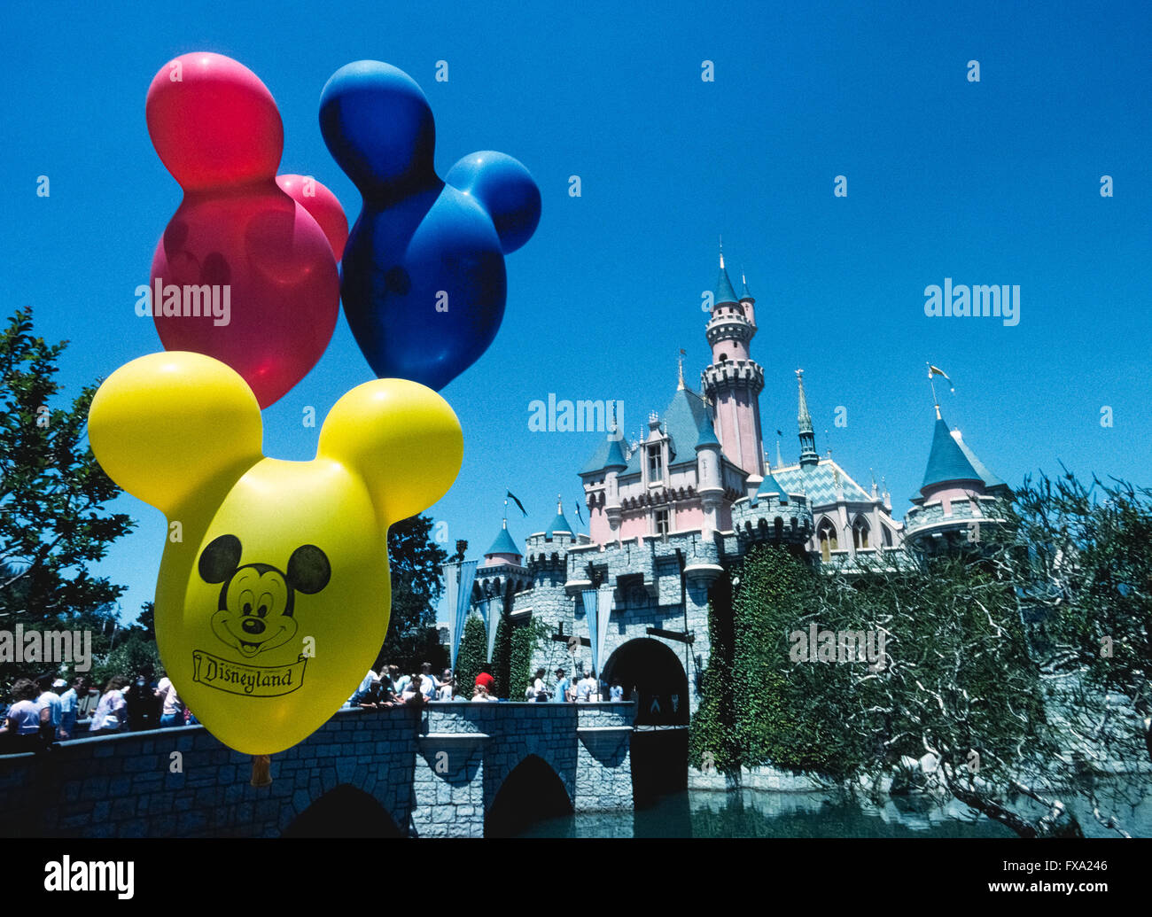 I colori vivaci dei palloncini con la faccia di Topolino galleggiante nella parte anteriore di Sleeping Beauty Castle, un imponente fiabesca struttura che è il fulcro di tutto il mondo più famoso parco a tema Disneyland, che ha aperto nel 1955 in Anaheim, California, USA. L'edificio è stato modellato dopo un vero e proprio castello, Neuschwanstein, costruiti in Germania nel tardo Ottocento come un palazzo di Re Ludwig II di Baviera. Disneyland è stato la creazione di Walt Disney, un ben noto imprenditore americano e il regista che ha creato Mickey Mouse e altri leggendari personaggi dei cartoni animati. Foto Stock