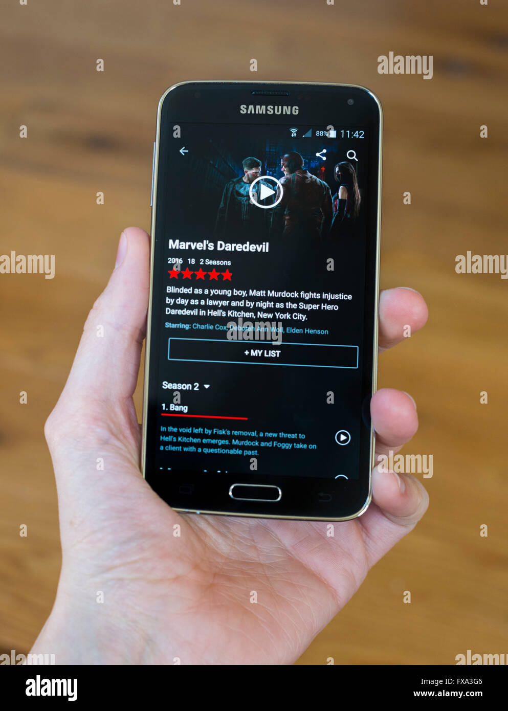 Una mano che tiene un telefono Samsung con le app Netlfix aperto e mostra il televisore visualizza il temerario. Foto Stock