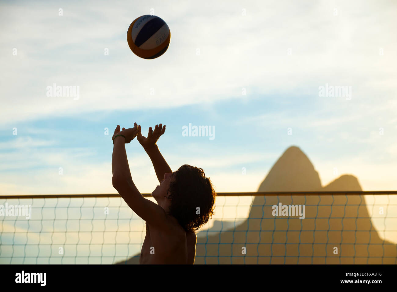 RIO DE JANEIRO - MARZO 20, 2016: pallavolo giocatore salta per la palla in un gioco al tramonto sulla spiaggia di Ipanema. Foto Stock