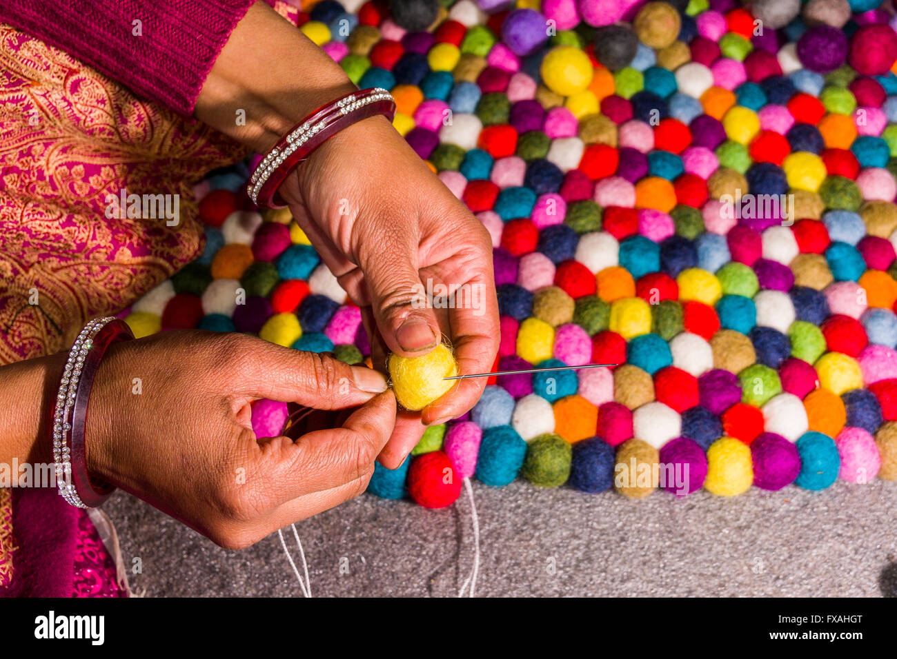Le mani di una donna sono la produzione di un tappeto di feltro sfere, Kathmandu, Nepal Foto Stock