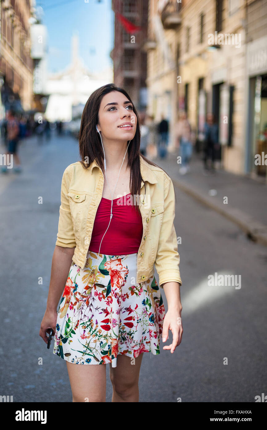 Giovane donna graziosa passeggiate in città in estate sorridente e guardando fuori Foto Stock
