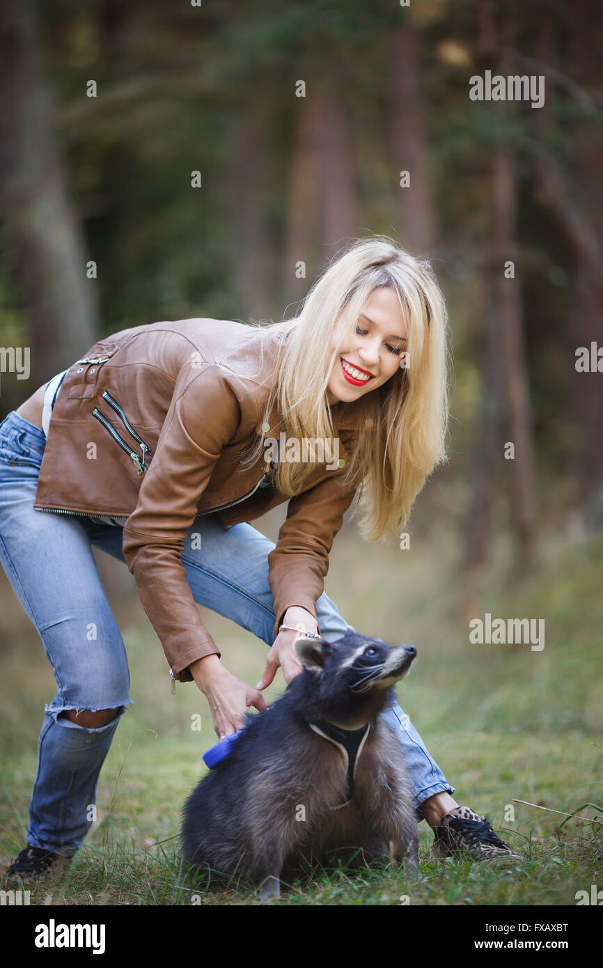 Ritratto di attraente giovane donna con raccoon in una foresta Foto Stock