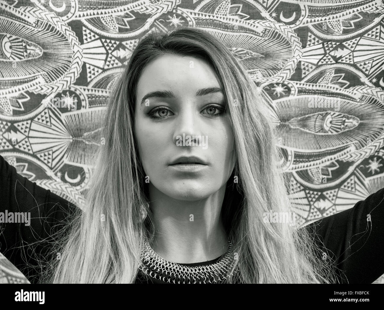 Ritratto di attraente ragazza bionda in abito nero, outdoor guardando la telecamera, giocando con sciarpa o foulard Foto Stock