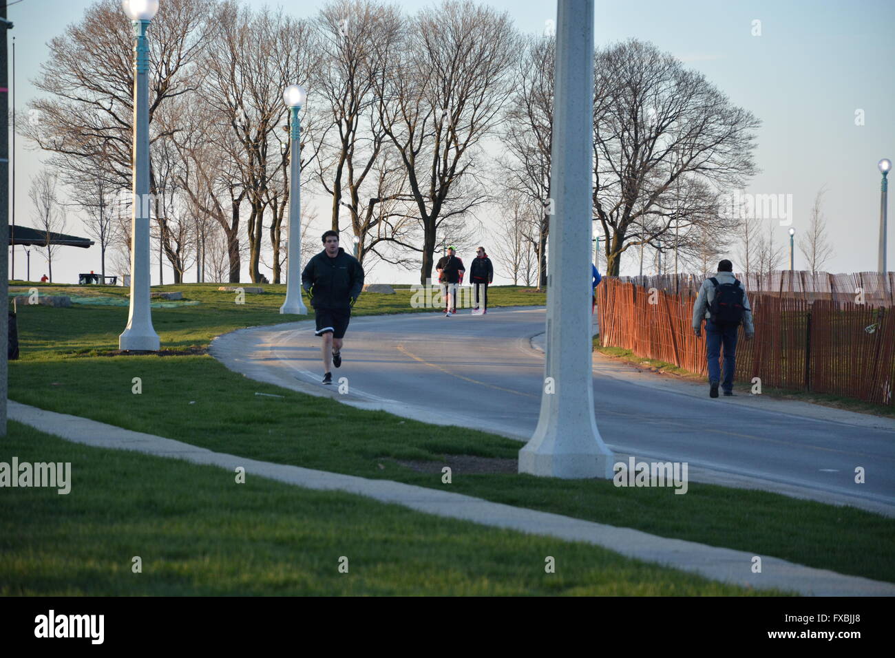 Per gli amanti del jogging correre passato scherma di neve sul lago percorso di corsa durante una serata primaverile a Fullerton Avenue, Chicago, Illinois, Stati Uniti d'America. Foto Stock