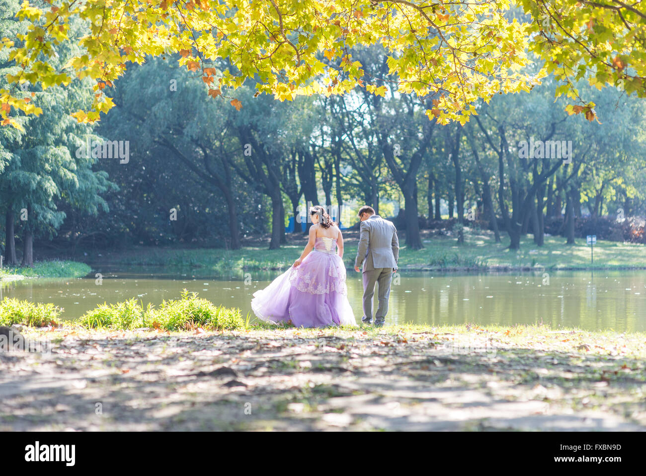 Coppia giovane tenendo il telefono di nozze in un parco Foto Stock