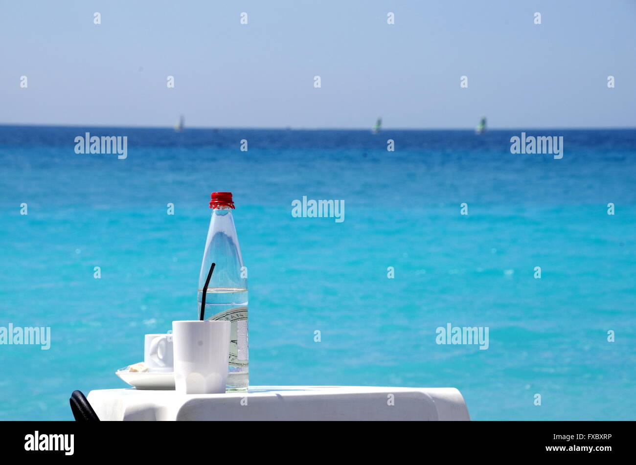 Acqua in bottiglia e la tazza di caffè sulla spiaggia di una tabella Foto Stock