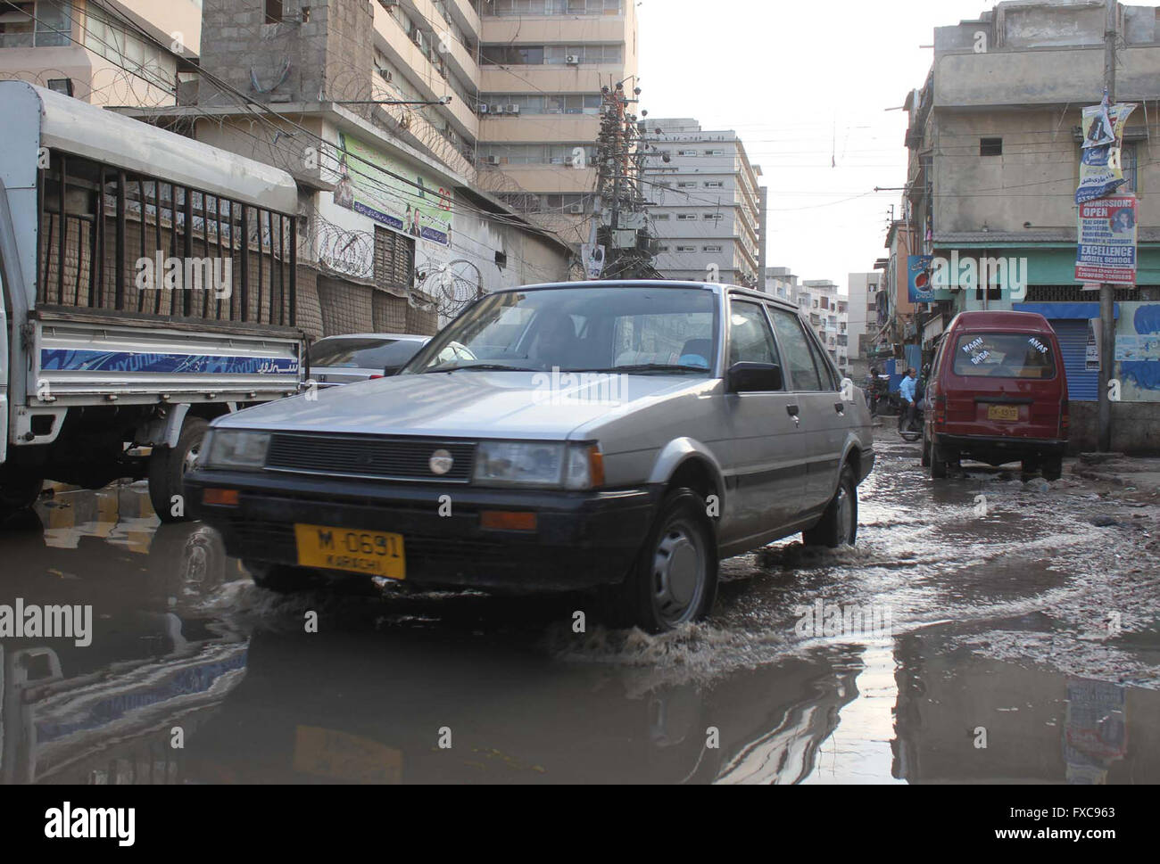 Pendolari che passa attraverso la rete fognaria di ristagno di acqua dietro il segretariato del Sindh edificio a Kamal Ataturk Road a Karachi il giovedì 14 aprile, 2016. Foto Stock