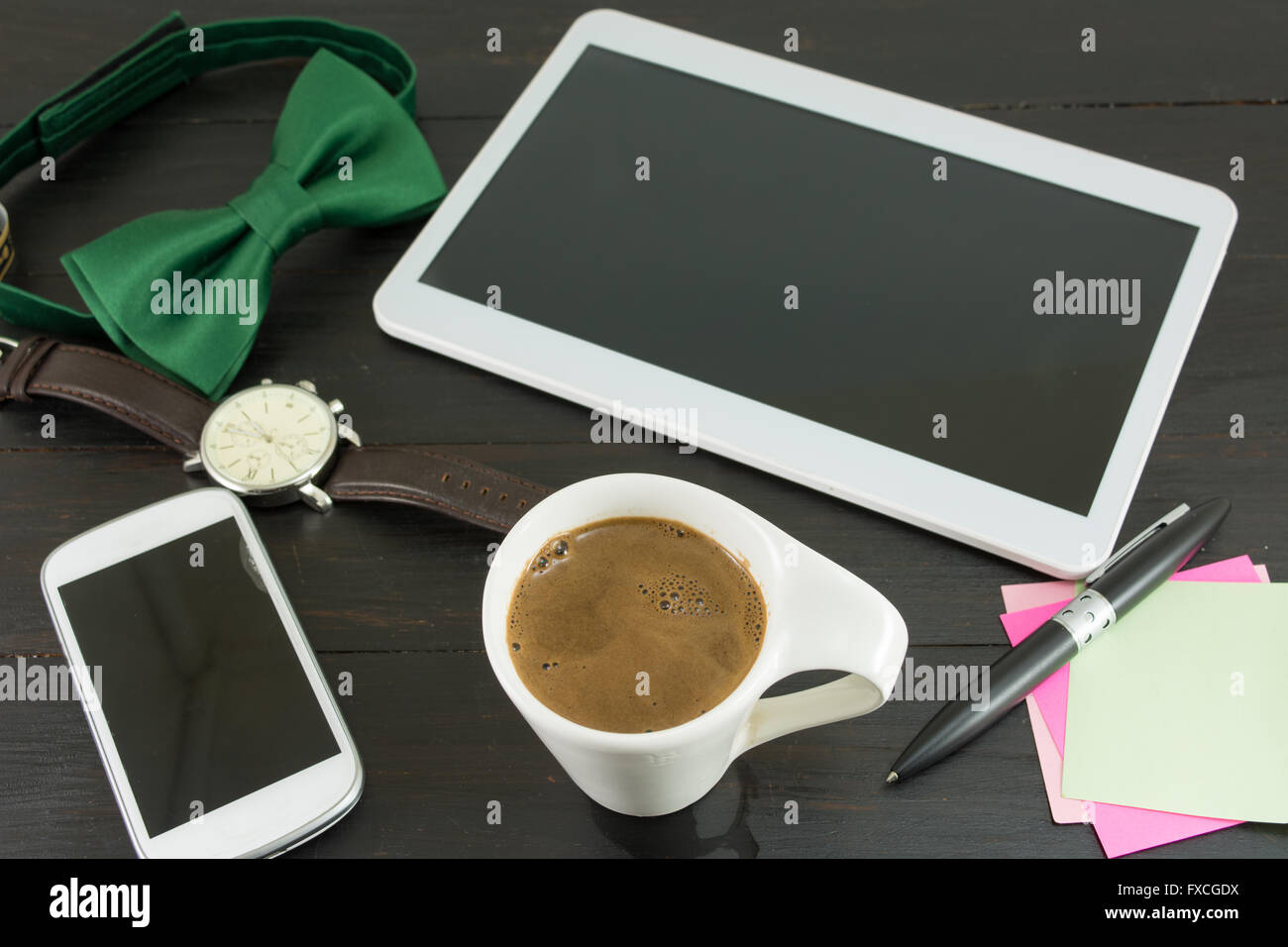 Tazza di caffè per una buona giornata di lavoro. Caffè e tech accessori sulla tavola nera Foto Stock