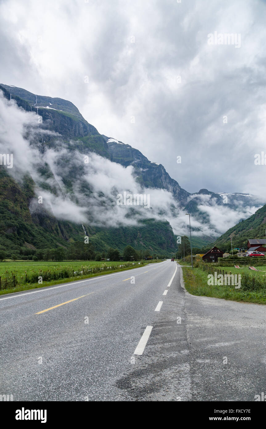 Misty Mountains coperto da nuvole e vanishing road vicino al villaggio di Gudvangen, Norvegia Foto Stock