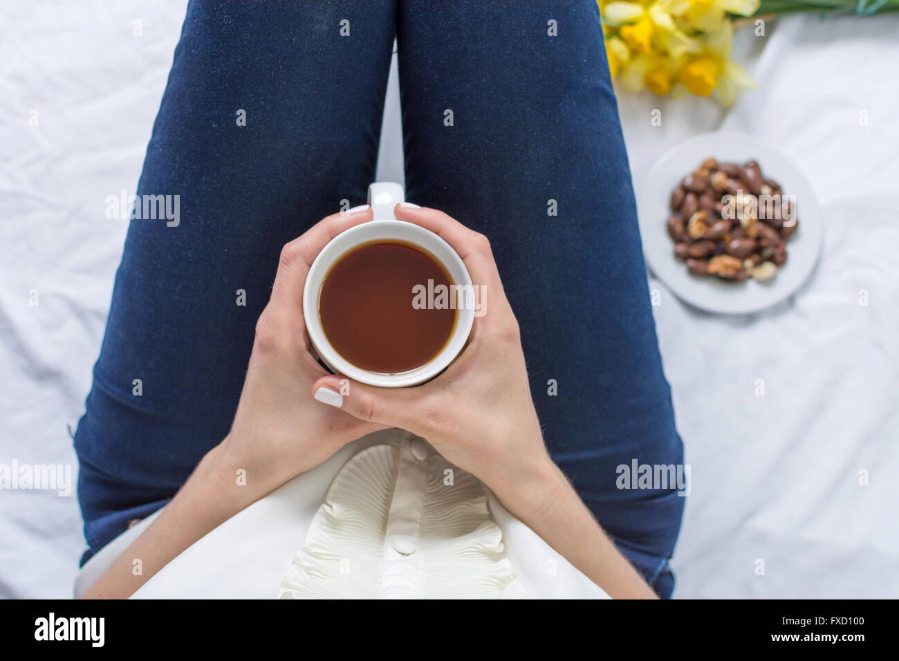 Donna con una tazza di tè prima di lavorare a letto Foto Stock