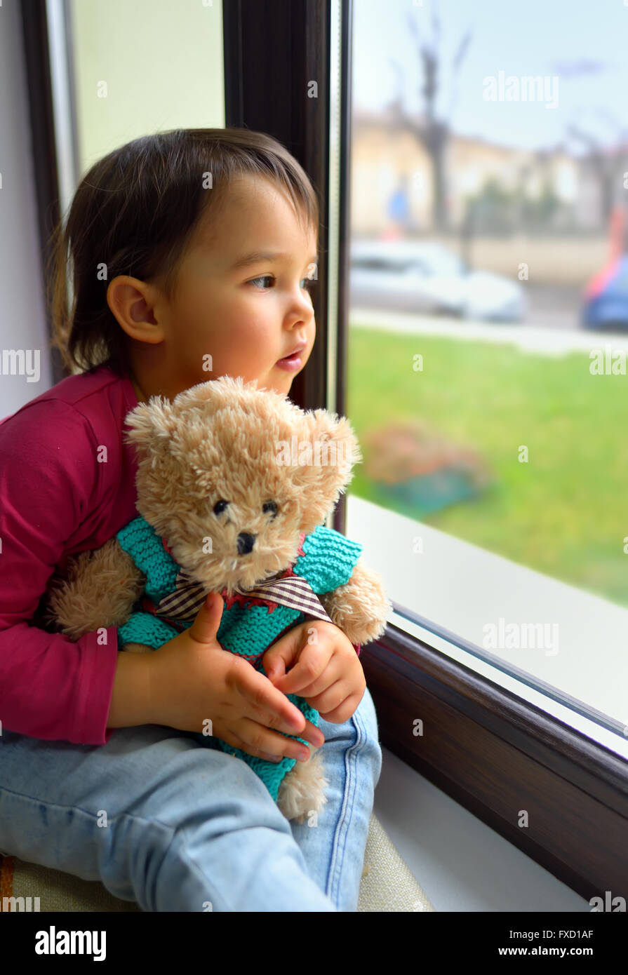 Bambina guardando fuori dalla finestra a casa Foto Stock