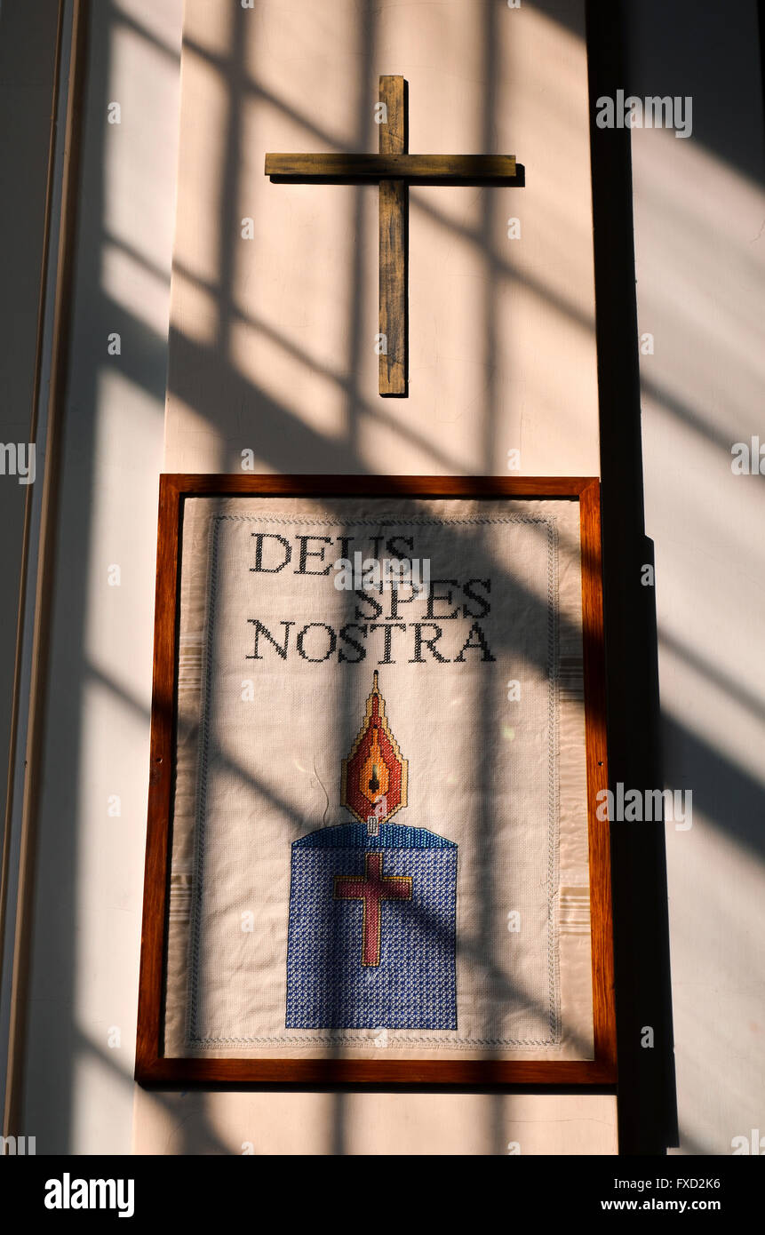 La luce attraverso una finestra su di un arazzo latina con iscrizione e croce di legno. deus spes nostra. Dio è la nostra speranza! Foto Stock
