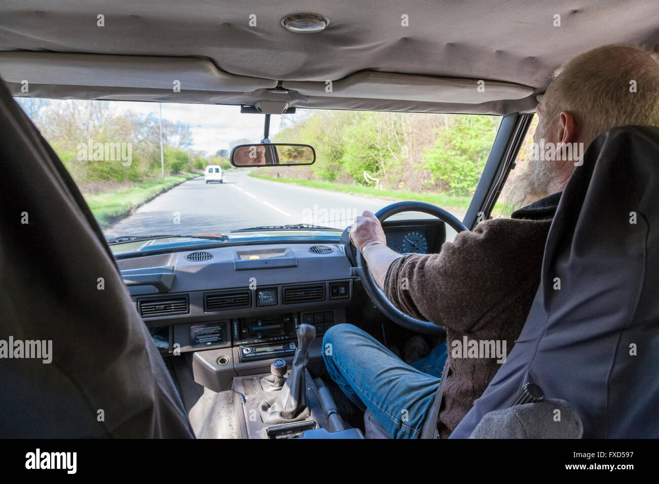 Uomo alla guida di una vettura su una strada, Nottinghamshire, Inghilterra, Regno Unito. Vista dall'interno di un Range Rover. Foto Stock