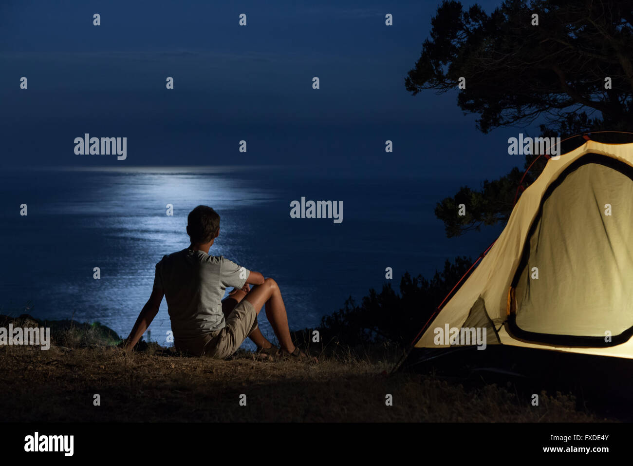 Uomo vicino alla tenda illuminata di notte Foto Stock