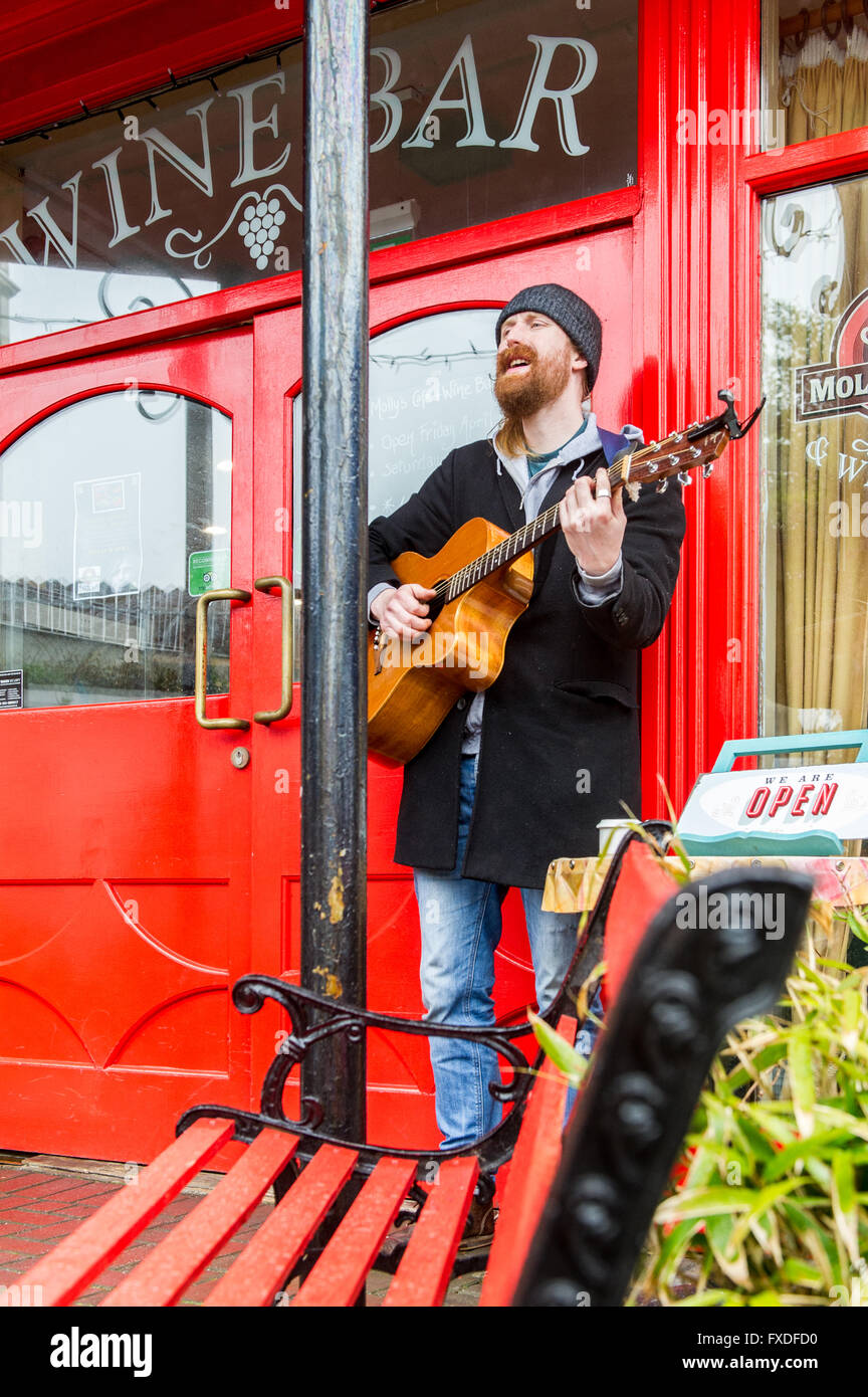 Un suonatore ambulante svolge al di fuori di un wine bar in Clonakilty, West Cork, Irlanda. Foto Stock