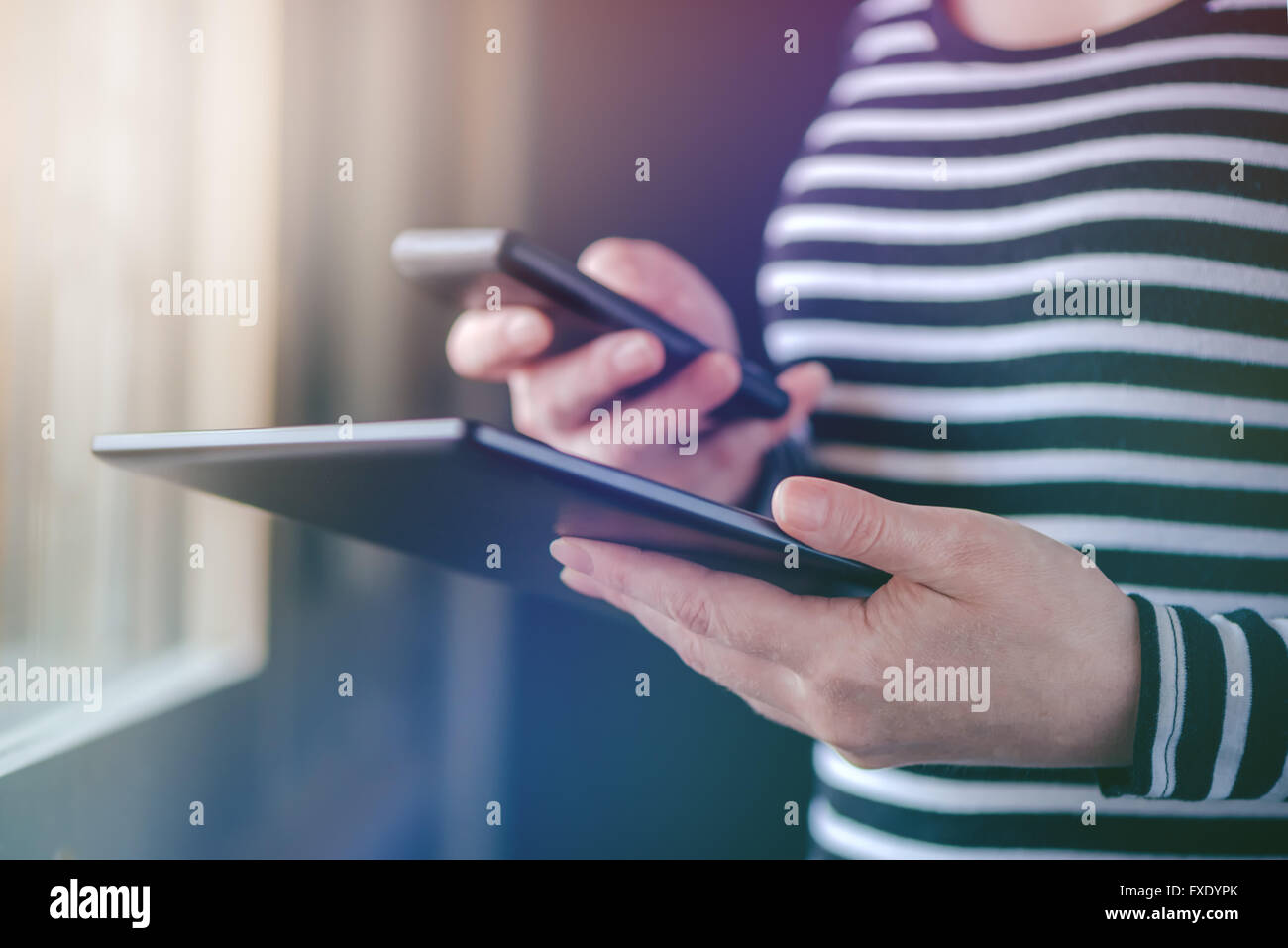 Smartphone e Tablet la sincronizzazione dei dati, la donna la sincronizzazione di file e documenti su personal wireless dispositivi elettronici a casa, s Foto Stock
