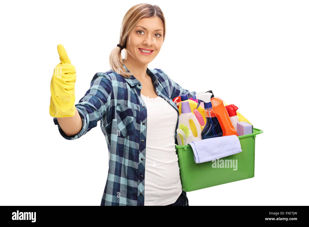 Allegro ragazza con un mazzetto di prodotti di pulizia e dando un pollice in alto isolato su sfondo bianco Foto Stock