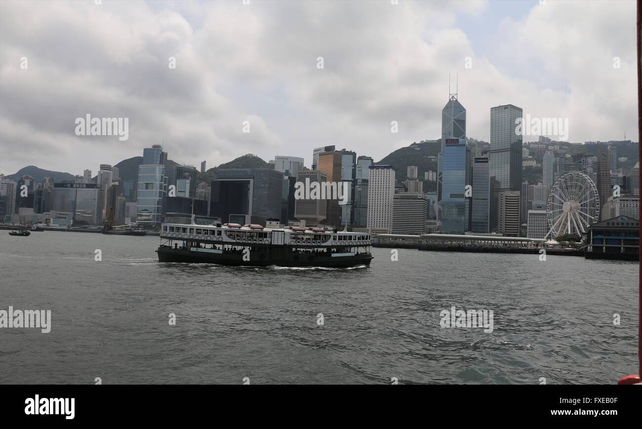 Skyline di Hong Kong con un traghetto Star Ferry Crossing Victoria Harbour in un pomeriggio nebuloso. Foto Stock