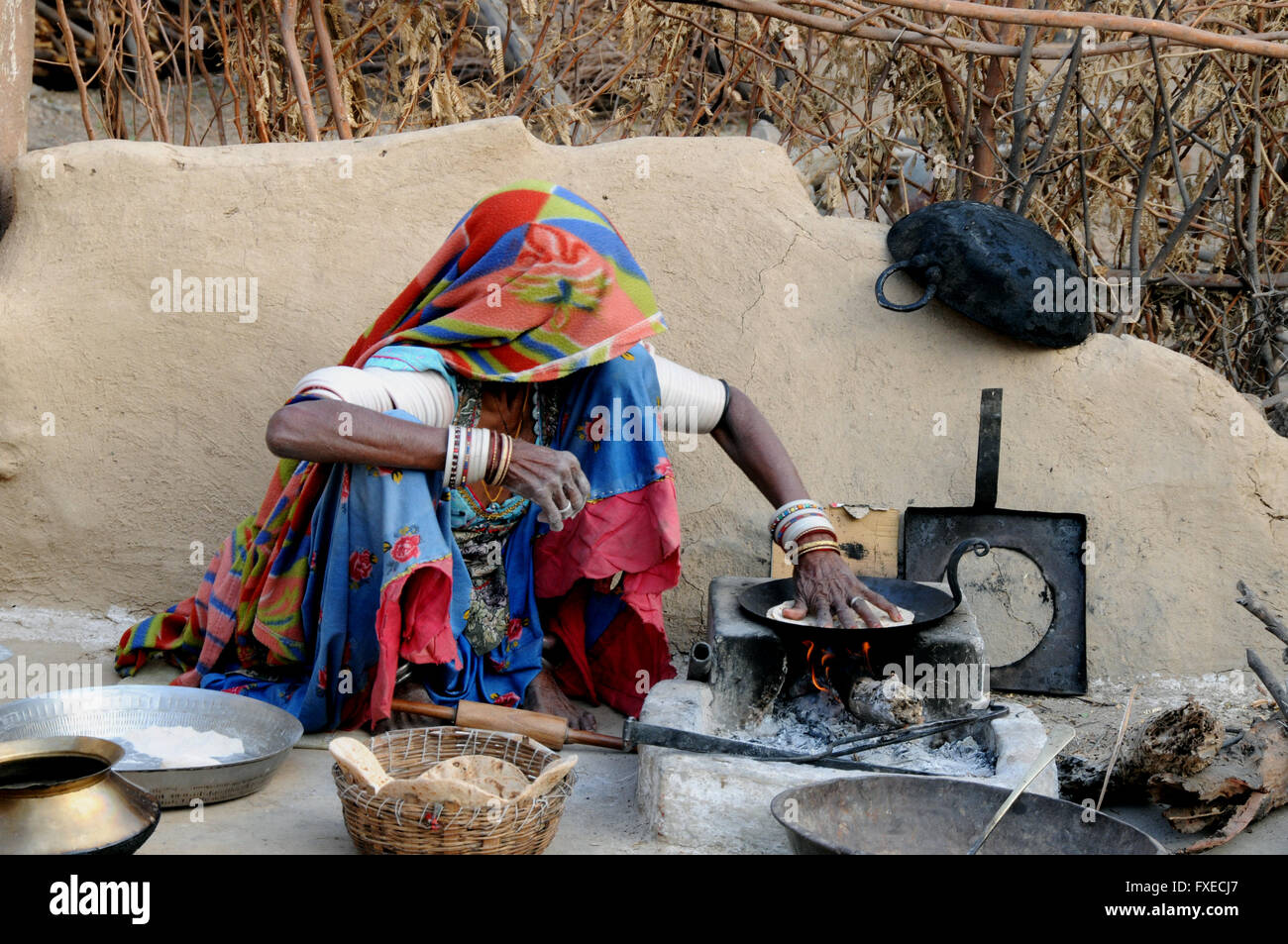 Una donna si siede rendendo la sua colazione della mattina presto chapatis in un villaggio vicino al nord della città indiana di Jojawar. Foto Stock