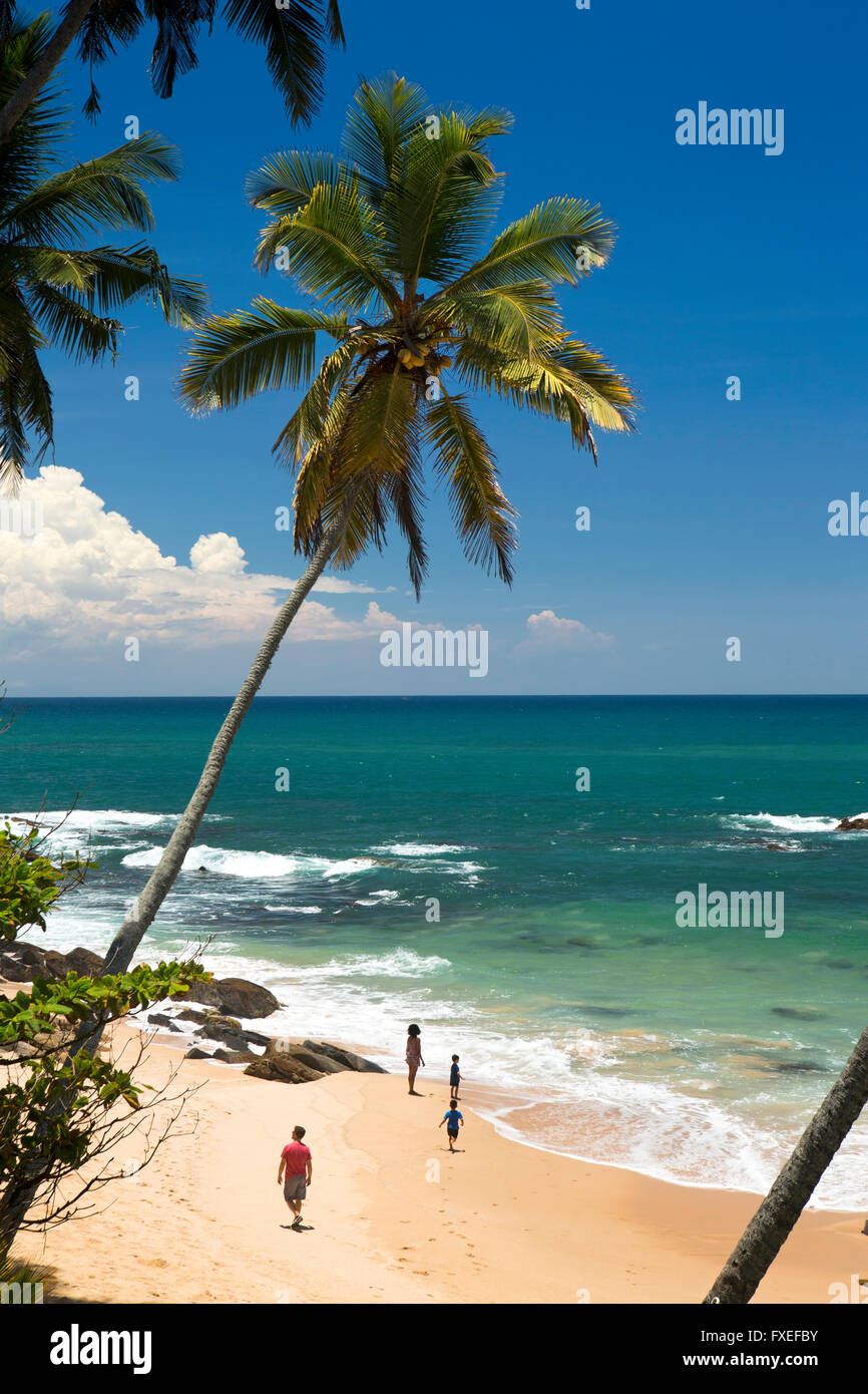 Sri Lanka, Tangalle, giovane famiglia rilassante sulla spiaggia tropicale idilliaco Foto Stock