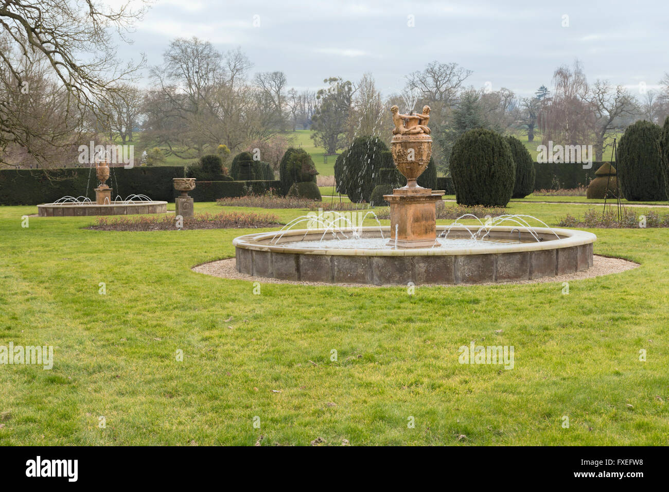 Fontane e topiaria da nel sud giardini presso Burghley House, una cinquecentesca di country house, Stamford, Inghilterra, Regno Unito. Foto Stock