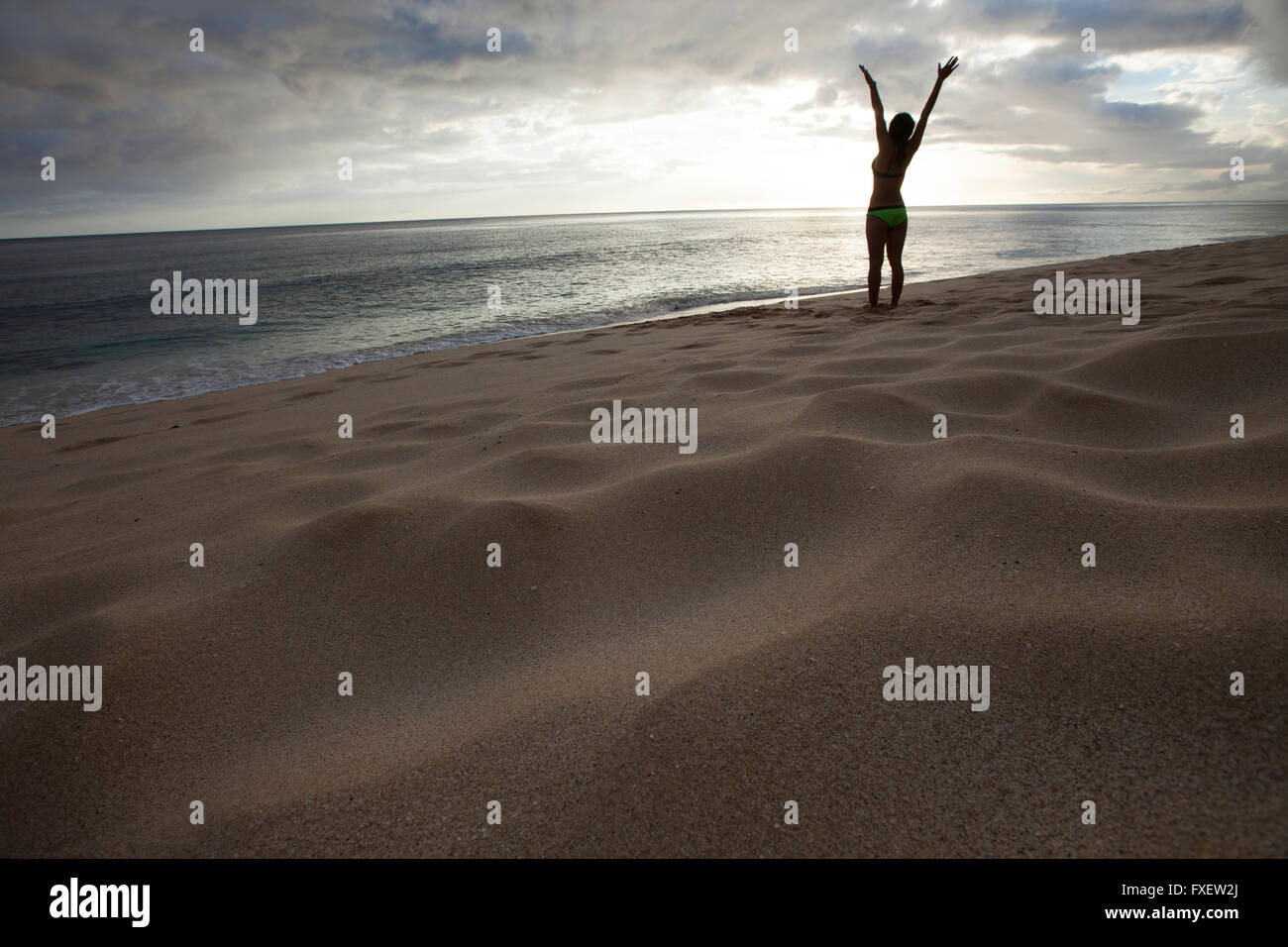 Giovane donna stretching e giocare al litorale, Keawaula Beach, West Oahu, Hawaii Foto Stock