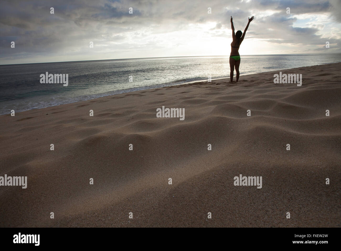 Giovane donna stretching e giocare al litorale, Keawaula Beach, West Oahu, Hawaii Foto Stock