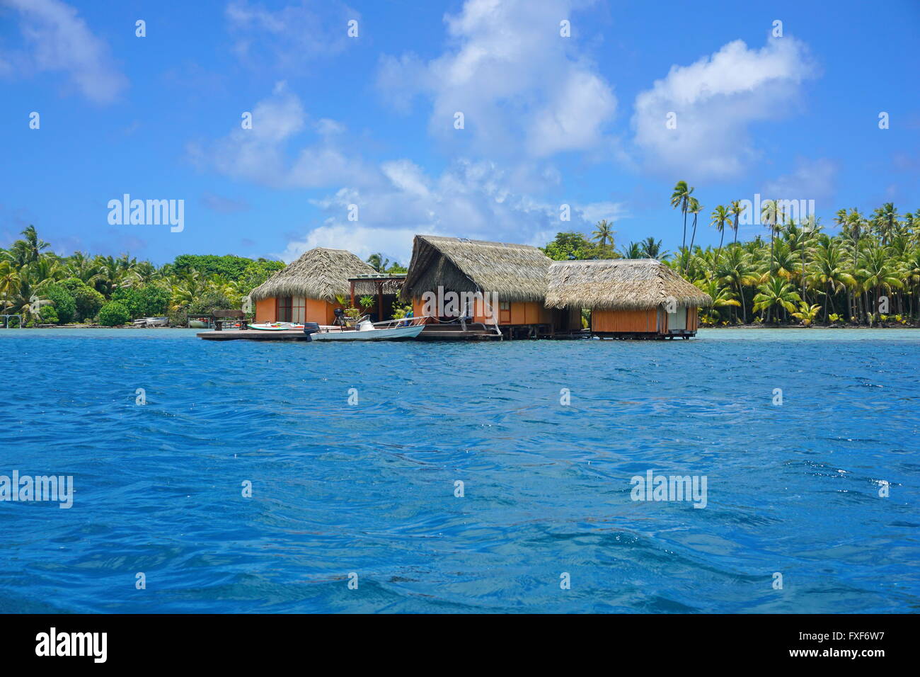 Casa tropicale con tetto di paglia su acqua con riva di un isolotto in background, Huahine isola, oceano pacifico, Polinesia Francese Foto Stock