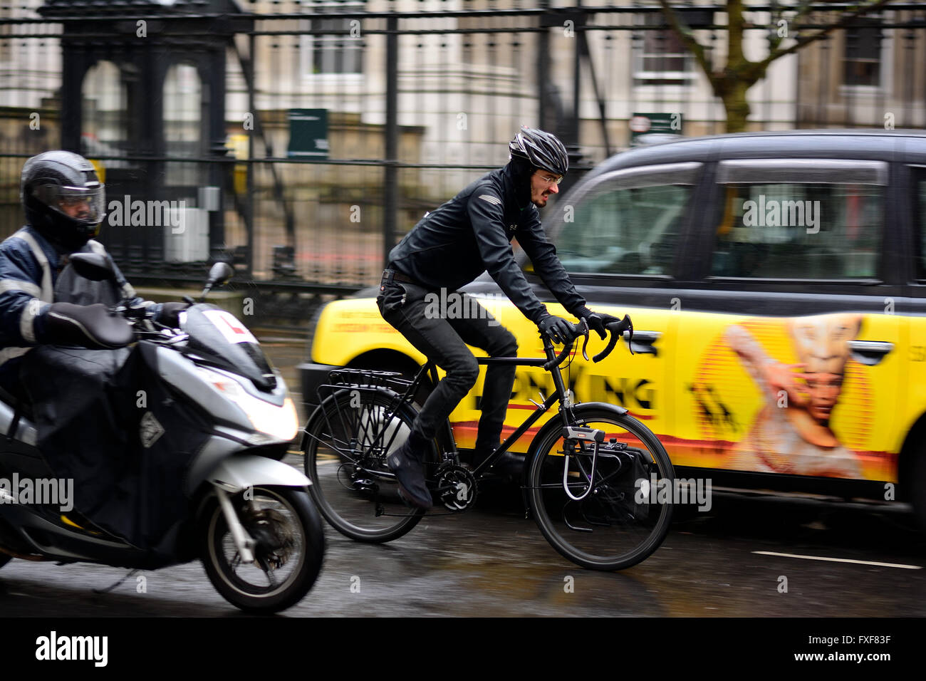Ciclista tra traffico in wet weather in London Foto Stock